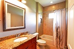 Guest bath featuring wood cabinetry and granite tops